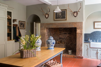 ロンドンにあるお手頃価格の広いカントリー風のおしゃれな家事室 (御影石カウンター、緑の壁、テラコッタタイルの床、グレーのキャビネット) の写真