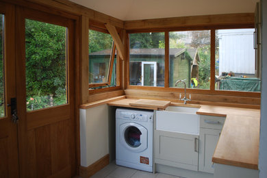 Photo of a small traditional utility room in Other with a belfast sink, wood worktops, brown worktops and beige walls.