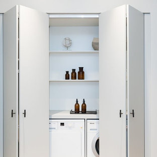 Idées déco pour une buanderie linéaire contemporaine avec un placard, un placard sans porte, des portes de placard blanches, des machines côte à côte et un plan de travail blanc.