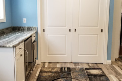 Utility room - mid-sized contemporary galley light wood floor and gray floor utility room idea in Cleveland with an undermount sink, recessed-panel cabinets, white cabinets, granite countertops, blue walls, a side-by-side washer/dryer and multicolored countertops