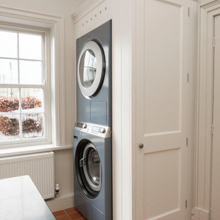 Idéer för att renovera ett mellanstort vintage svart u-format svart grovkök, med en rustik diskho, luckor med infälld panel, vita skåp, granitbänkskiva, beige väggar, klinkergolv i terrakotta, en tvättpelare och orange golv