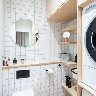 Ispirazione per una piccola lavanderia multiuso nordica con lavatoio, ante lisce, ante in legno chiaro, top in legno, paraspruzzi bianco, paraspruzzi con piastrelle in ceramica, pareti bianche, pavimento in sughero, lavatrice e asciugatrice a colonna e pavimento marrone