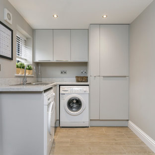 This is an example of a contemporary l-shaped separated utility room in Belfast with a built-in sink, flat-panel cabinets, grey cabinets, engineered stone countertops, grey walls, a side by side washer and dryer, brown floors and grey worktops.