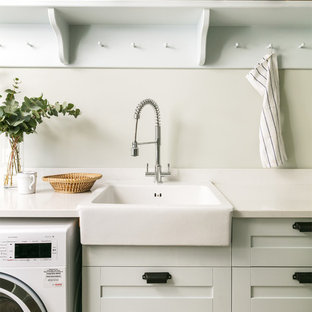Inspiration for a nautical utility room in London with a belfast sink, shaker cabinets, grey cabinets, grey walls and white worktops.