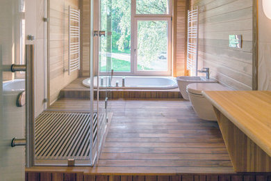 他の地域にある広いコンテンポラリースタイルのおしゃれなマスターバスルーム (壁掛け式トイレ、磁器タイル、無垢フローリング、木製洗面台、ドロップイン型浴槽) の写真