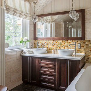 Inredning av ett klassiskt mellanstort vit vitt en-suite badrum, med luckor med infälld panel, skåp i mörkt trä, en toalettstol med separat cisternkåpa, beige kakel, gul kakel, orange kakel, travertinkakel, beige väggar, klinkergolv i keramik, bänkskiva i akrylsten, brunt golv, ett fristående handfat och ett platsbyggt badkar