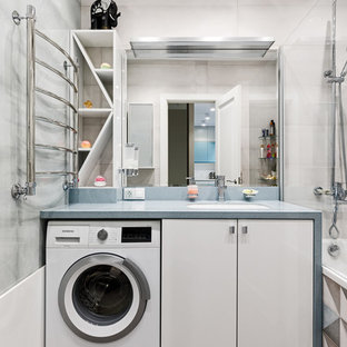 Aménagement d'une petit salle de bain principale scandinave avec un placard à porte plane, des portes de placard blanches, une baignoire encastrée, un WC suspendu, un carrelage gris, des carreaux de céramique, un mur gris, un sol en carrelage de céramique, un lavabo encastré, un plan de toilette en surface solide, un sol marron et un plan de toilette turquoise.