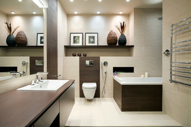 Idéer för att renovera ett mellanstort funkis brun brunt badrum, med släta luckor, skåp i mörkt trä, ett badkar i en alkov, beige kakel, porslinskakel, beige väggar, klinkergolv i porslin, träbänkskiva, en vägghängd toalettstol och ett nedsänkt handfat