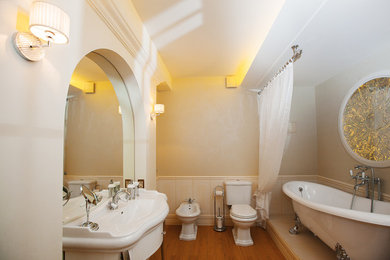 На фото: главная ванная комната среднего размера в стиле неоклассика (современная классика) с ванной на ножках, бежевой плиткой, керамогранитной плиткой, бежевыми стенами, полом из керамической плитки, консольной раковиной и раздельным унитазом с