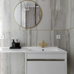 Nordisk inredning av ett mellanstort vit vitt en-suite badrum, med släta luckor, vita skåp, en dusch i en alkov, en vägghängd toalettstol, grå kakel, porslinskakel, grå väggar, klinkergolv i keramik, ett väggmonterat handfat, bänkskiva i akrylsten, vitt golv och dusch med duschdraperi