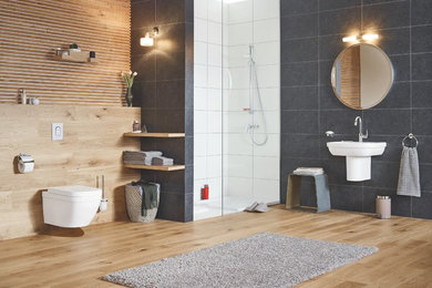 Ejemplo de cuarto de baño contemporáneo con ducha empotrada, sanitario de pared, aseo y ducha, lavabo suspendido y suelo marrón