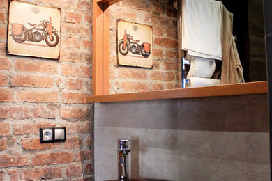 Industriell inredning av ett mellanstort en-suite badrum, med öppna hyllor, ett fristående badkar, en vägghängd toalettstol, grå kakel, porslinskakel, klinkergolv i porslin, ett fristående handfat, träbänkskiva och svart golv