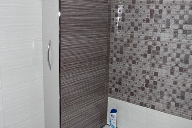 モスクワにある低価格の小さなコンテンポラリースタイルのおしゃれなマスターバスルーム (フラットパネル扉のキャビネット、グレーのキャビネット、アルコーブ型浴槽、グレーのタイル) の写真