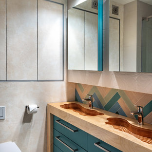 Immagine di una stanza da bagno design con ante lisce, ante turchesi, lavabo integrato, top in legno, pavimento beige e top marrone