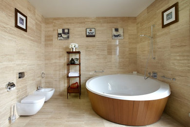 На фото: главная ванная комната в современном стиле с отдельно стоящей ванной, душем над ванной, инсталляцией и бежевой плиткой с