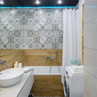 Modern inredning av ett litet grå grått en-suite badrum, med släta luckor, vita skåp, en dusch/badkar-kombination, porslinskakel, klinkergolv i porslin, laminatbänkskiva, grått golv, dusch med duschdraperi, ett badkar i en alkov, grå kakel och ett fristående handfat