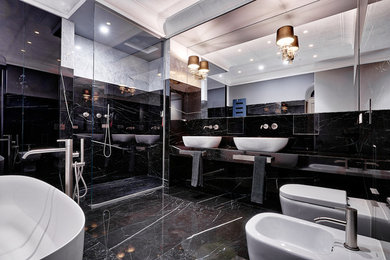 Стильный дизайн: главная ванная комната в современном стиле с отдельно стоящей ванной, душем без бортиков, биде, черной плиткой, настольной раковиной и черным полом - последний тренд