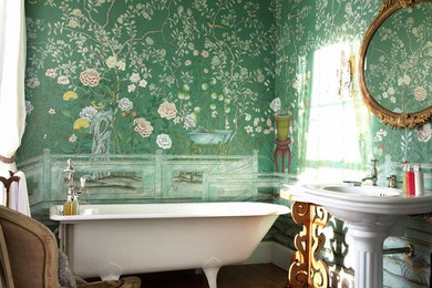 На фото: главная ванная комната в викторианском стиле с ванной на ножках, зелеными стенами, раковиной с пьедесталом и коричневым полом