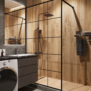 This is an example of a mid-sized industrial 3/4 bathroom in Other with flat-panel cabinets, grey cabinets, an alcove shower, a wall-mount toilet, gray tile, porcelain tile, grey walls, porcelain floors, an undermount sink, solid surface benchtops, grey floor, a shower curtain, black benchtops, a laundry, a single vanity and a floating vanity.