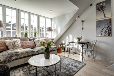 Diseño de salón abierto nórdico sin chimenea con paredes grises, suelo de madera clara y suelo beige