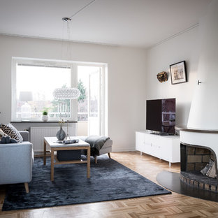 Idéer för minimalistiska separata vardagsrum, med vita väggar, mellanmörkt trägolv, en standard öppen spis, en spiselkrans i gips, en fristående TV och brunt golv