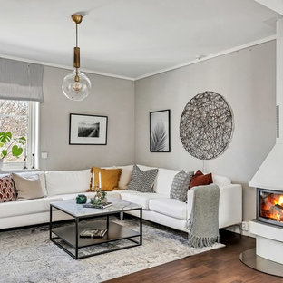 Inspiration för mellanstora nordiska separata vardagsrum, med grå väggar, mellanmörkt trägolv, brunt golv, en dubbelsidig öppen spis och en spiselkrans i metall