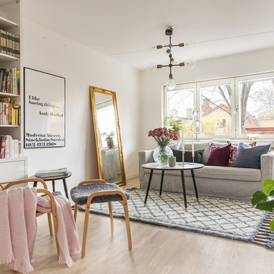 Example of a large danish formal and enclosed light wood floor living room design in Stockholm with white walls and no tv