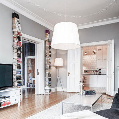 Example of a large danish formal and open concept light wood floor living room design in Gothenburg with gray walls and a tv stand