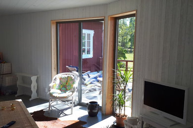 Mittelgroßes, Offenes Country Wohnzimmer ohne Kamin mit weißer Wandfarbe, Betonboden und freistehendem TV in Göteborg
