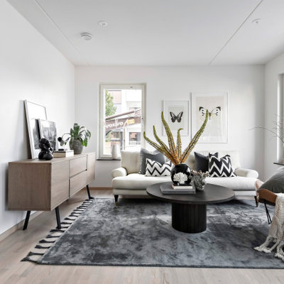 Danish formal light wood floor and beige floor living room photo in Stockholm with white walls, no fireplace and no tv