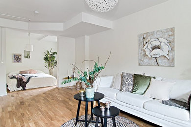 Offenes Skandinavisches Wohnzimmer ohne Kamin mit weißer Wandfarbe und braunem Holzboden in Stockholm
