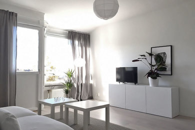 Danish enclosed light wood floor living room photo in Orebro with white walls, no fireplace and a tv stand