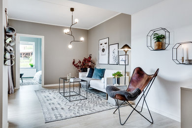 Ejemplo de salón abierto escandinavo de tamaño medio sin televisor con paredes beige, suelo de madera clara y suelo gris
