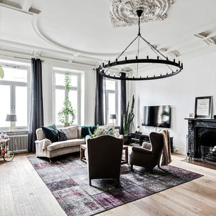 Foto på ett stort vintage vardagsrum, med vita väggar, ljust trägolv, en standard öppen spis, en spiselkrans i sten, en väggmonterad TV och beiget golv