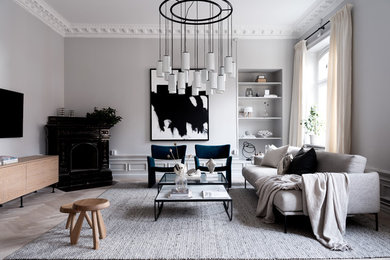 Imagen de salón actual con paredes grises, suelo de madera clara, chimenea de esquina, televisor colgado en la pared y suelo gris