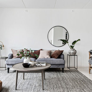 Minimalistisk inredning av ett mellanstort separat vardagsrum, med vita väggar, ljust trägolv och beiget golv