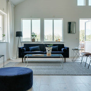 Inredning av ett modernt stort allrum med öppen planlösning, med vita väggar, beiget golv och ljust trägolv
