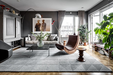 Ejemplo de salón para visitas abierto nórdico grande sin chimenea con paredes grises, televisor retractable y suelo de madera en tonos medios