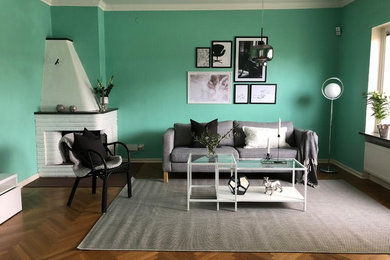 Inspiration pour un grand salon minimaliste fermé avec un mur vert, un sol en bois brun, une cheminée d'angle, aucun téléviseur, un sol marron et un manteau de cheminée en brique.