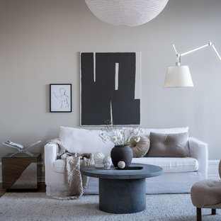 Idéer för att renovera ett minimalistiskt vardagsrum, med grå väggar, mellanmörkt trägolv och brunt golv