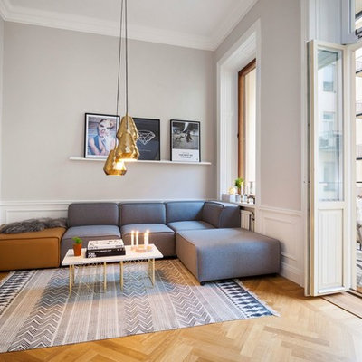 Example of a large danish formal and open concept medium tone wood floor living room design in Stockholm with gray walls, no fireplace and a wall-mounted tv
