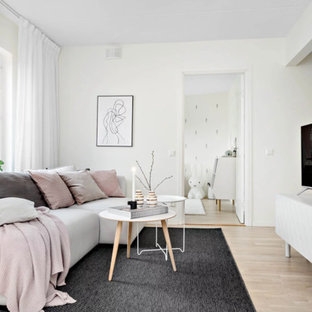 Inspiration för ett mellanstort minimalistiskt allrum med öppen planlösning, med vita väggar, ljust trägolv, en fristående TV och beiget golv