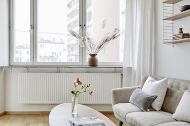 Kleines, Offenes Modernes Wohnzimmer mit weißer Wandfarbe und hellem Holzboden in Stockholm