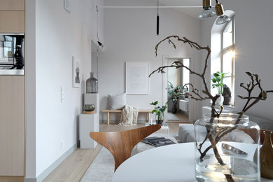 Inredning av ett minimalistiskt stort allrum med öppen planlösning, med ett finrum, grå väggar och ljust trägolv