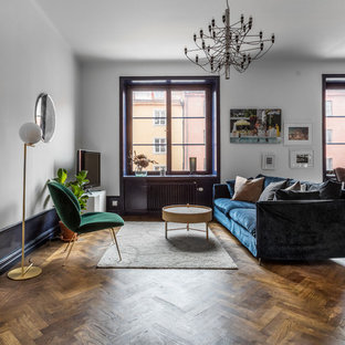 Exempel på ett stort minimalistiskt allrum med öppen planlösning, med vita väggar, mellanmörkt trägolv, brunt golv och en fristående TV