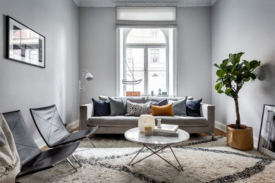 Cette image montre un grand salon nordique fermé avec un mur gris, une salle de réception, un sol en bois brun, aucun téléviseur et éclairage.