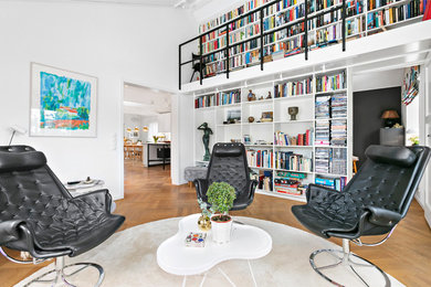 Exempel på ett minimalistiskt vardagsrum, med ett bibliotek, vita väggar och mellanmörkt trägolv