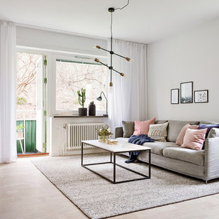 Bild på ett minimalistiskt vardagsrum, med vita väggar, ljust trägolv och beiget golv