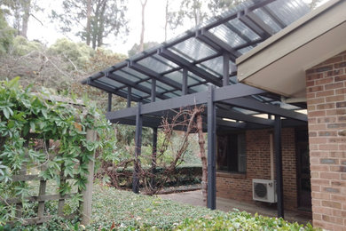 Idéer för en mellanstor modern veranda längs med huset, med naturstensplattor och en pergola