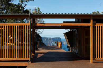 Exemple d'un porche d'entrée de maison avec une cuisine d'été, une terrasse en bois et une extension de toiture.